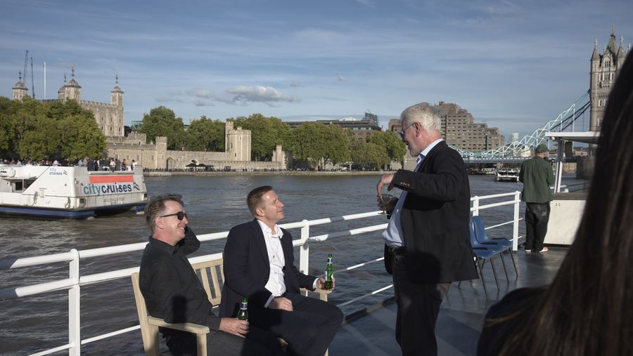Guests chat and relax on deck with the Tower of London and Tower Bridge behind them